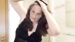 Mature woman with real silver strands slowly combs her long hair